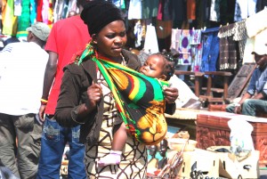 A mother carrying a baby  in front using a chitenje cloth in Lusaka. It is easier to breast feed the baby if needed.