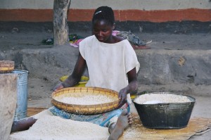 Girl using Chihengo or winning pounded maize in a village. Compose a poem about this in a Zambian language.